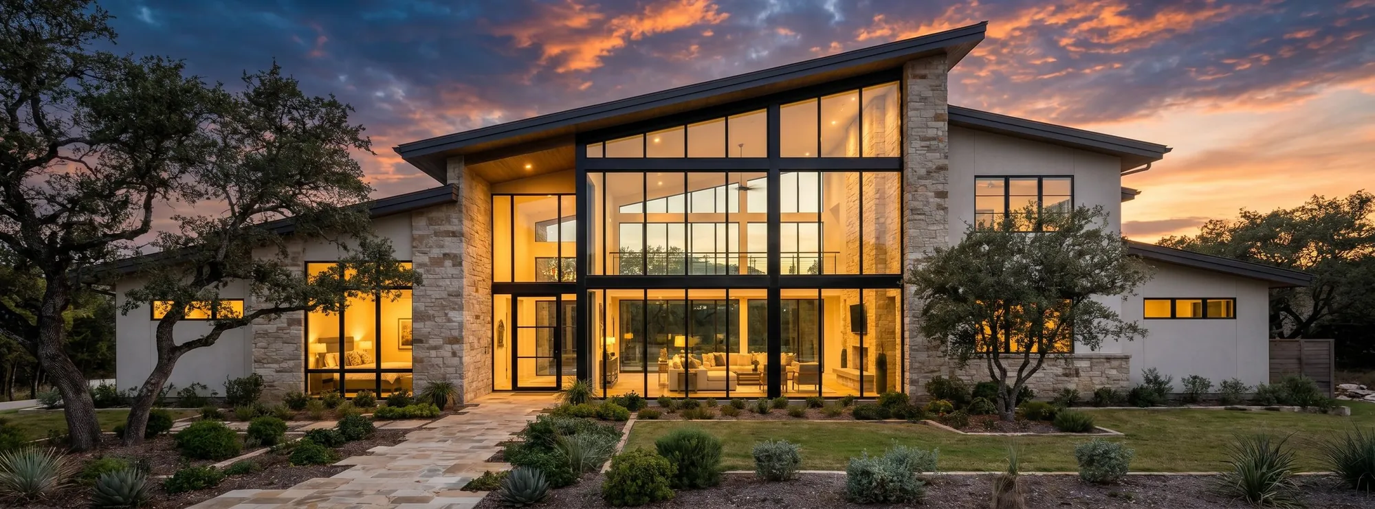 Hill country house at dusk, full-height aluminum glazing